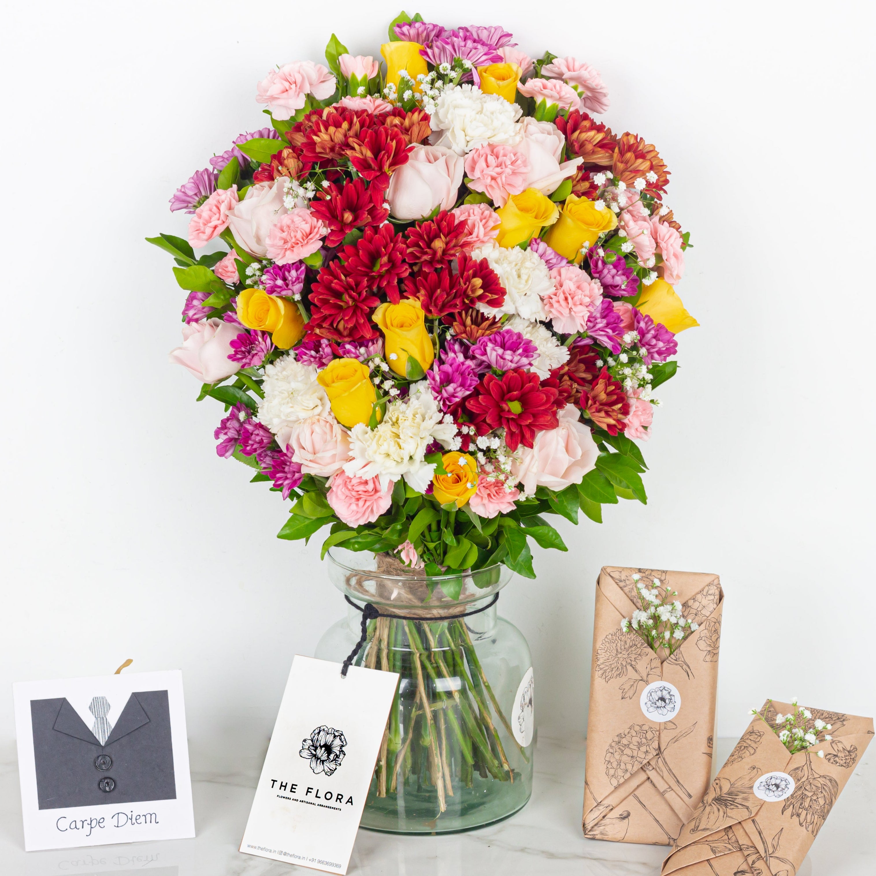 Colorful bouquet of flowers in a glass vase with branded packaging on a white background