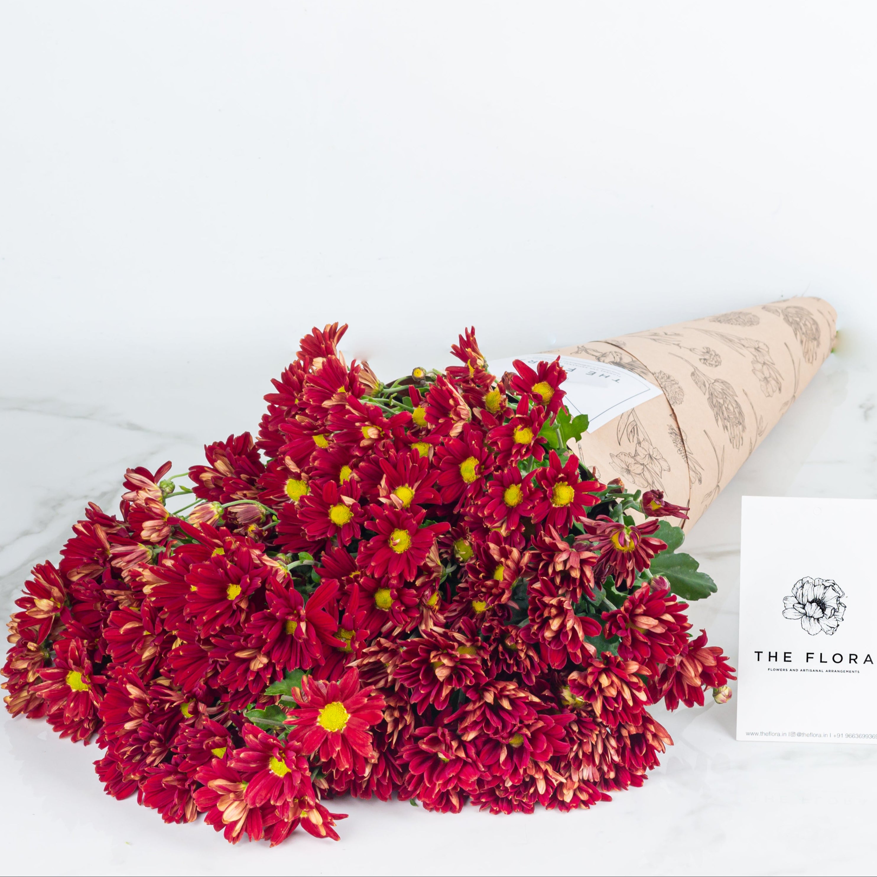 Bouquet of red Santini Chrysanthemums with 'The Flora' card. Online cut flowers n sustainable packaging from www.theflora.in