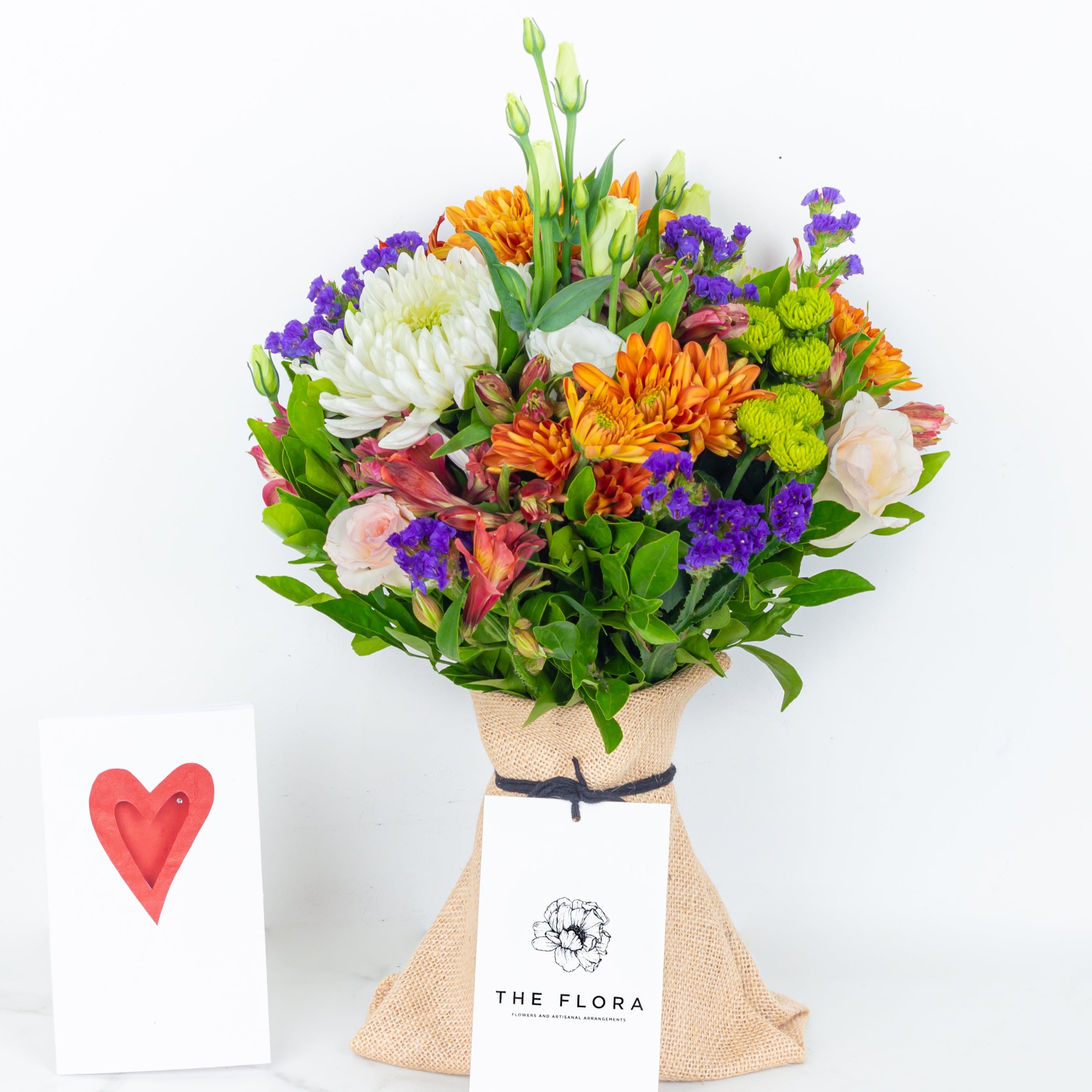 Colorful bouquet of flowers with a heart-shaped card. Guardian Grace with Alstroemeria, Lisianthus , Disbud Chrysanthemums, Blue Statice and Roses. Online artisanal bouquets with same day delivery in sustainable packaging at www.theflora.in