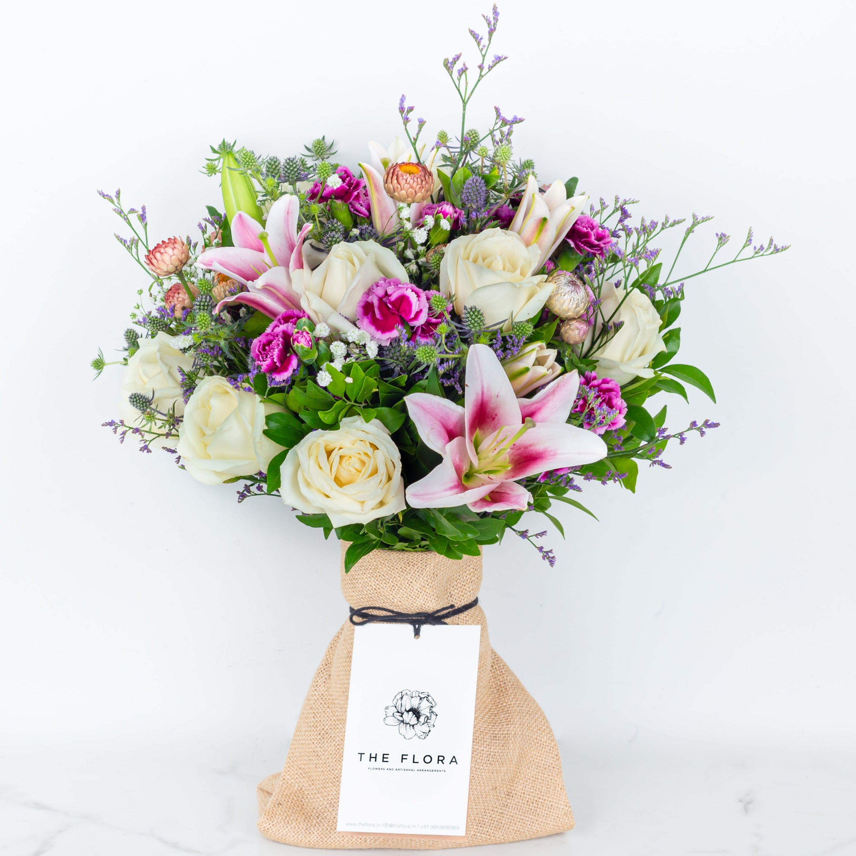 Bouquet of flowers in a paper bag called Soulful Strings. An artisanal bouquet of Eryngium, Roses, Oriental Lilies Helichrysum, Spray Carnations. and Limonium. Online artisanal bouquets with same day delivery in sustainable packaging at www.theflora.in