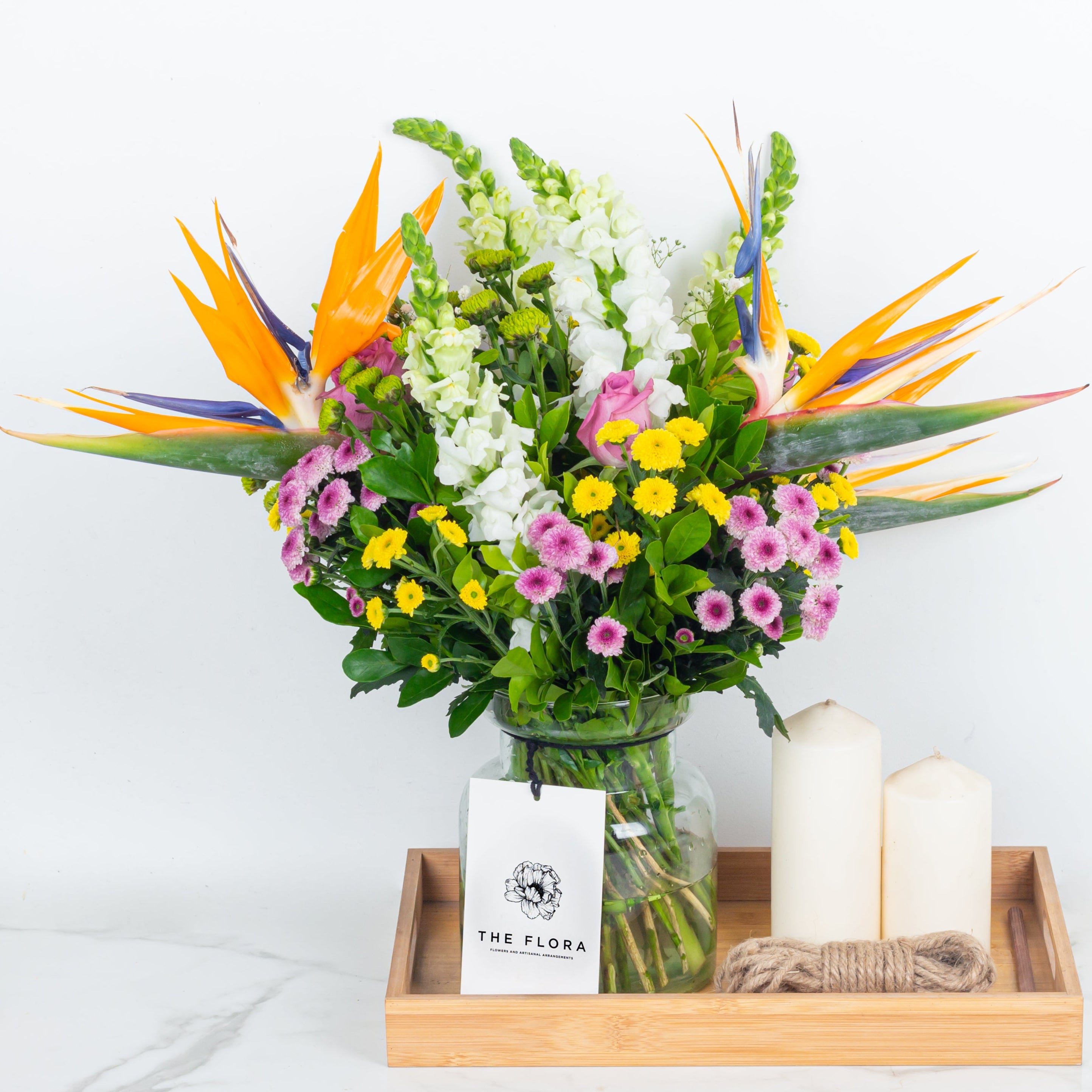 Bouquet of flowers with candles on a wooden tray called With All My Heart . An artisanal bouquet curated with Birds of Paradise, Button Chrysanthemums and roses. Online artisanal bouquets with same day delivery in sustainable packaging at www.theflora.in