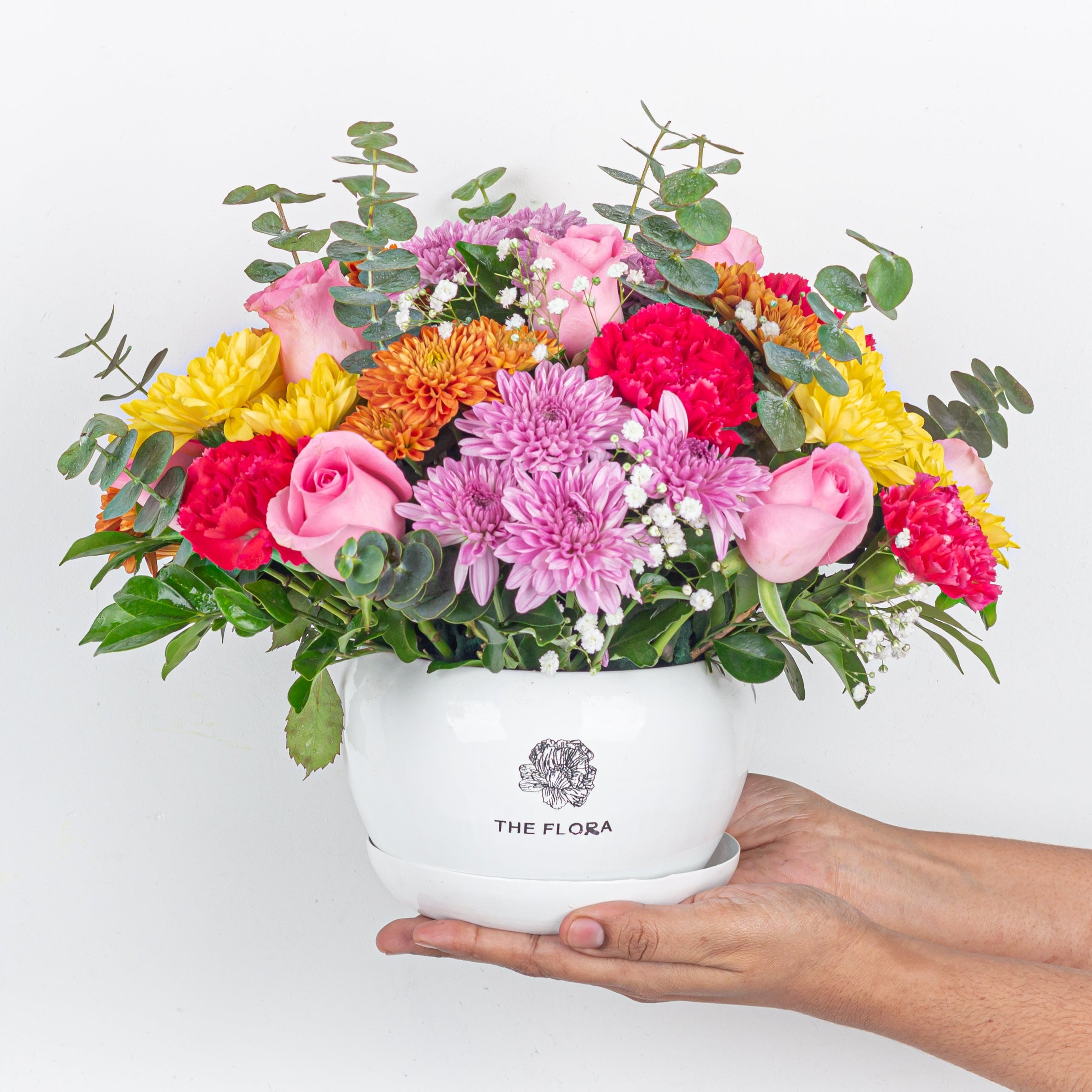 Rainbow Rhapsody flower arrangement in a metal pot comprising of roses carnations chrysanthemums Bangalore delivery held in hand