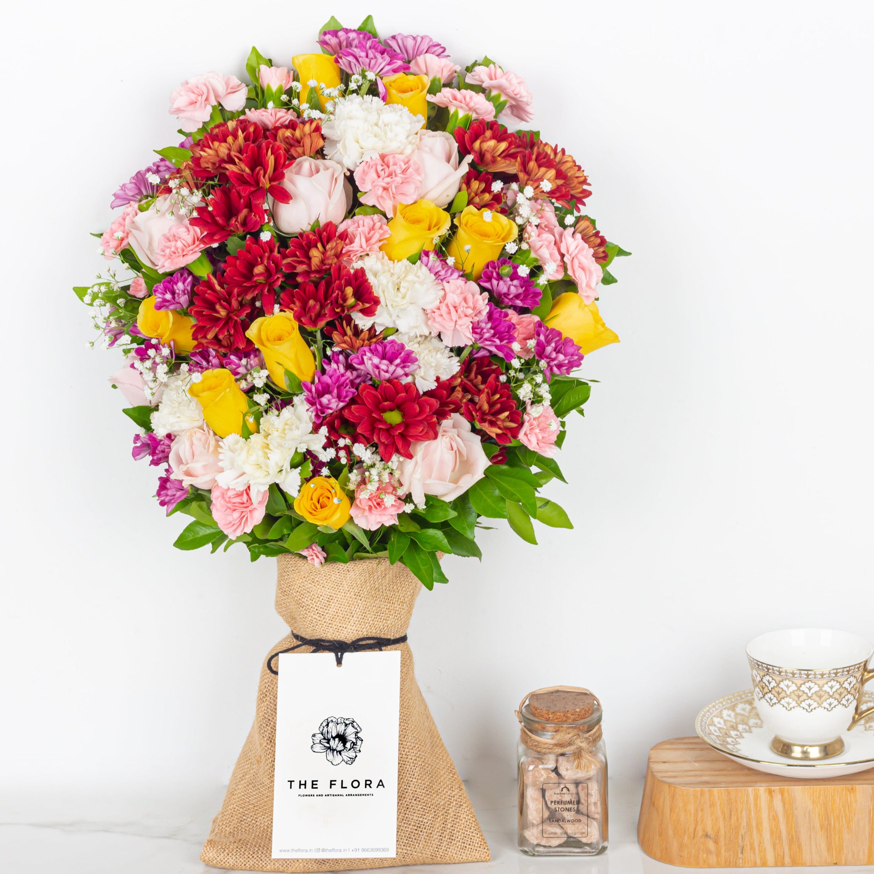 Colorful bouquet of flowers in a vase with 'The Flora' tag on a white background