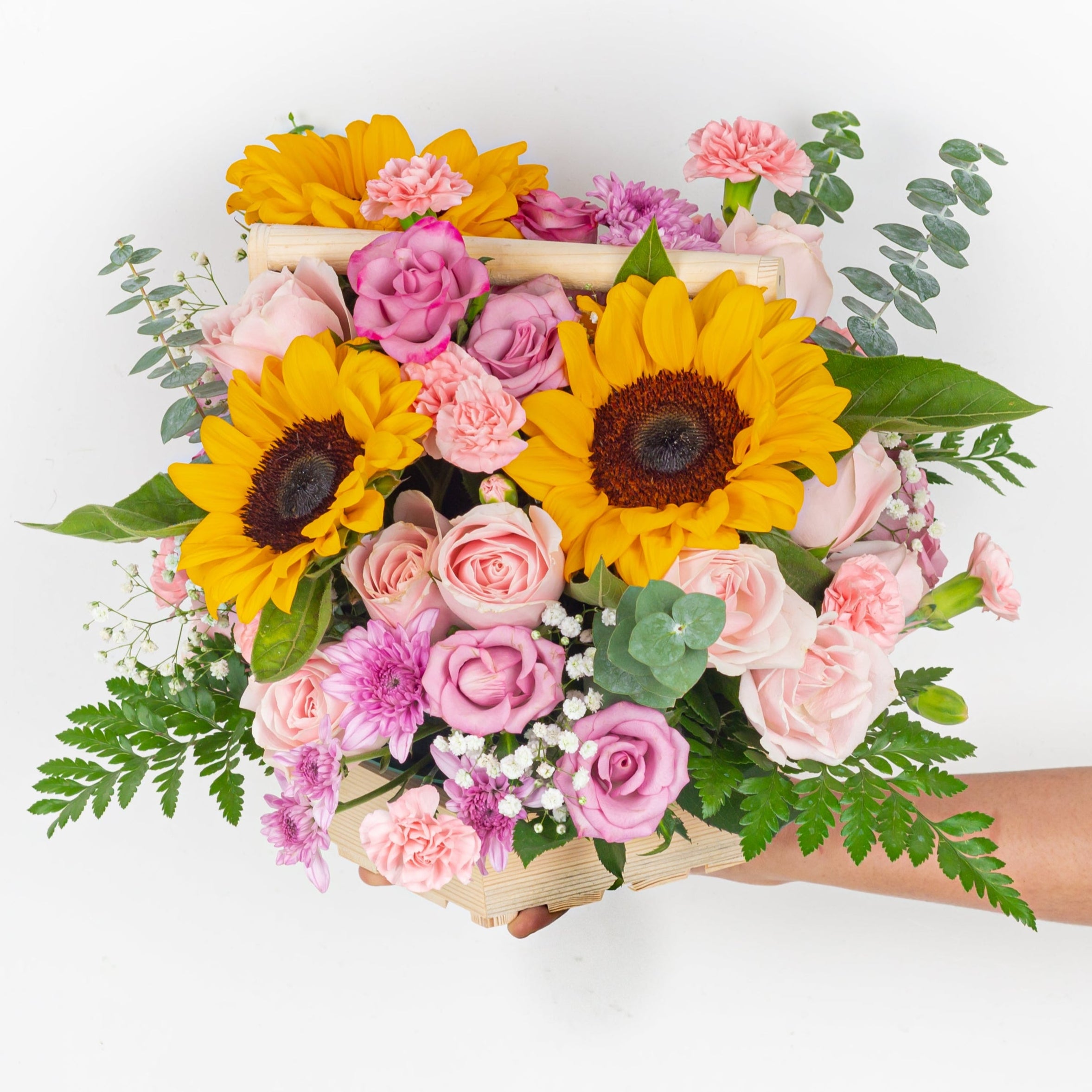 Bouquet of sunflowers and pink roses held by a person on a white background