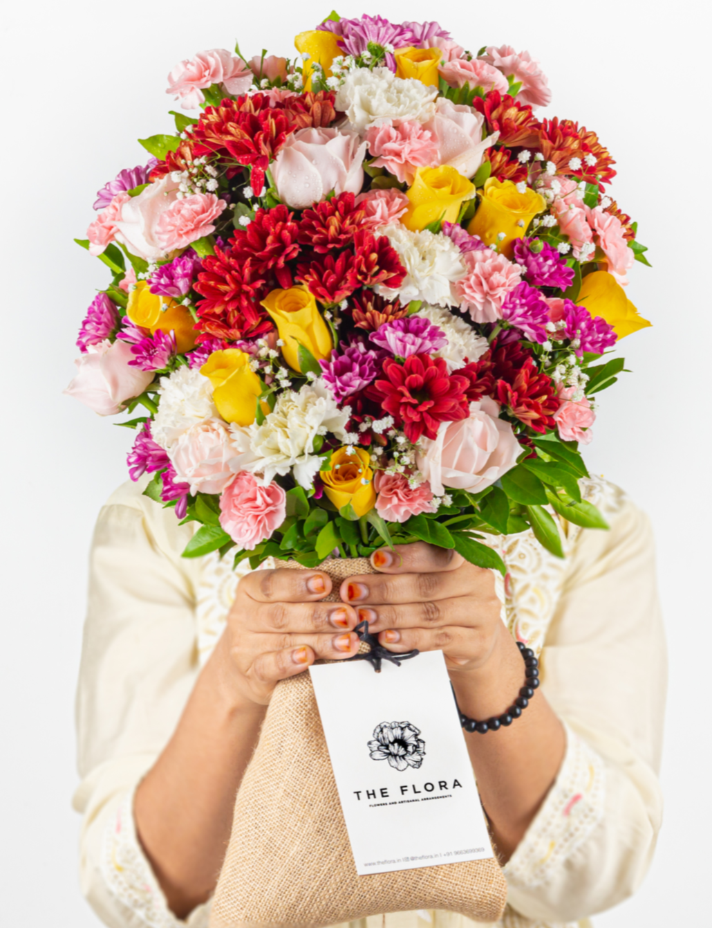 Bouquet of colorful flowers held by a person with a visible brand tag.