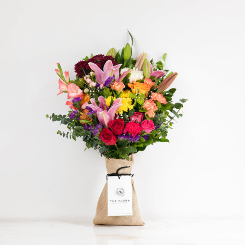 The Flora Riot of Colours bouquet, full view with burlap wrap and The Flora brand card